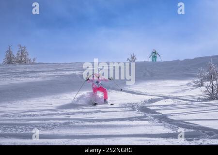 Due sciatori esperti percorrono con maestria una pista innevata splendidamente incontaminata, dimostrando l'emozione e il brivido degli sport invernali, il villaggio sciistico di Montgenevre, le Alpi, la Francia Foto Stock