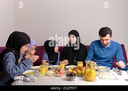 Una famiglia musulmana felice con cena iftar durante il Ramadan tavolo da pranzo a casa. Foto Stock
