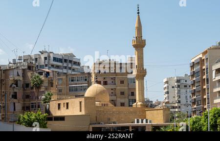 Nel cuore di una vivace città, si erge una bellissima moschea con un suggestivo minareto che raggiunge il cielo Foto Stock