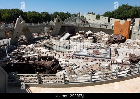 In un'area sviluppata, un grande mucchio di macerie è circondato da un'alta recinzione e da diversi alberi che si trovano nelle vicinanze, aggiungendo alla scena Foto Stock