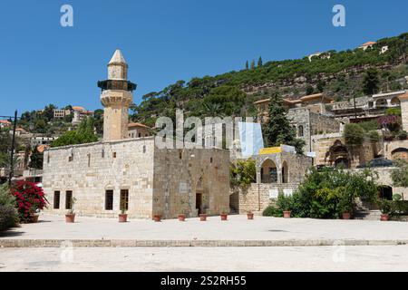 Nel centro di un affascinante villaggio, si erge una bellissima moschea adornata da un alto minareto che ne segna la presenza Foto Stock