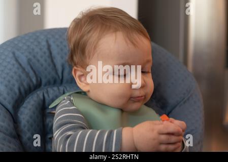 Il bambino sviluppa la pinza afferrando una carota Foto Stock