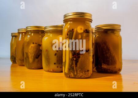 Vasi di vetro riempiti di cetrioli sottaceto su un tavolo di legno su sfondo bianco. Foto Stock