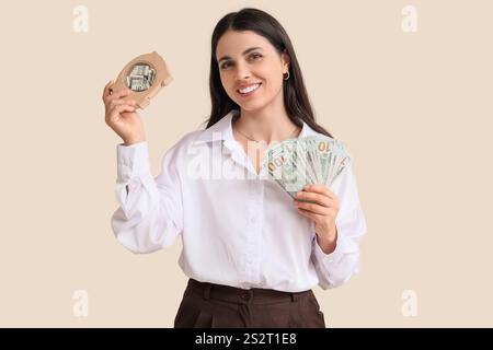 Bella donna con banconote da un dollaro e salvadanaio su sfondo beige Foto Stock