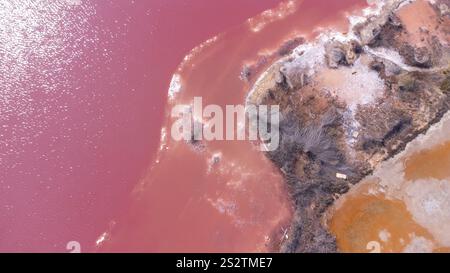 Vista aerea del lago di sale rosa di torrevieja, spagna, che riflette la luce del sole al tramonto, con la miniera di sale visibile in primo piano Foto Stock