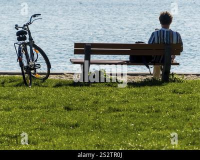 Un uomo siede con cura durante una pausa dal ciclismo in un parco vicino al lago Austria Foto Stock