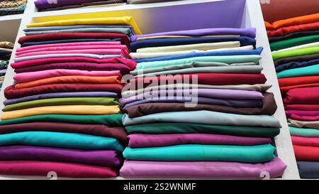 Una vivace e colorata pila di vari rotoli di tessuto in un negozio di artigianato Foto Stock