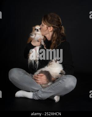 gatto siberiano, chihuahua e donna davanti a sfondo nero Foto Stock