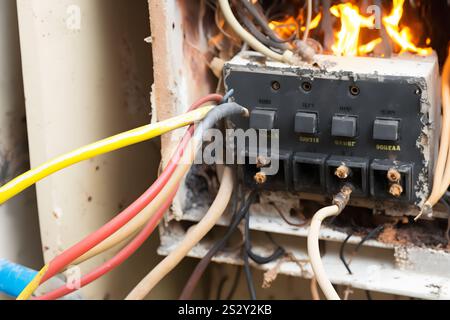 Combustione del quadro elettrico da sovraccarico o cortocircuito sulla parete. Interruttori automatici in caso di incendio e fumo causato da surriscaldamento a causa di un collegamento scadente. Rete neurale Foto Stock