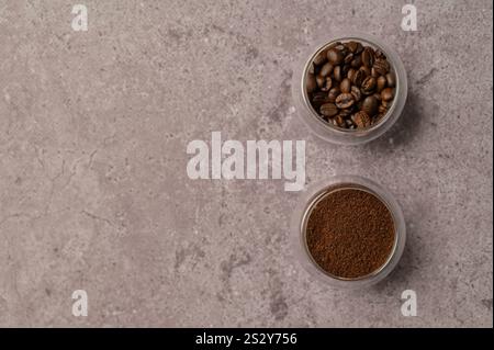 Vista dall'alto, caffè macinato e a grana aromatica fresco in piccoli bicchieri laterali, cemento grigio. Copia spazio sfondo, copertina, sfondo, trama Foto Stock