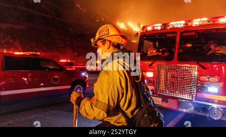 Malibu, California, Stati Uniti 7 gennaio 2025. Un Vigili del fuoco di LA County in un cappello da 89 è acceso rosso e giallo dalle luci dei veicoli di emergenza. Un incendio scoppiò il 7 gennaio 2025, come si vede dalla PCH (Pacific Coast Highway) nella ricca città di Pacific Palisades, ai margini di Malibu, CA, a causa di venti di Santa Ana insolitamente forti che superavano i 100 MPH (Credit Image: © Amy Katz/ZUMA Press Wire) SOLO PER L'USO EDITORIALE! Non per USO commerciale! Foto Stock