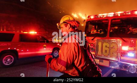Malibu, California, Stati Uniti 7 gennaio 2025. Un Vigili del fuoco di LA County in un cappello da 89 è acceso rosso e giallo dalle luci dei veicoli di emergenza. Un incendio scoppiò il 7 gennaio 2025, come si vede dalla PCH (Pacific Coast Highway) nella ricca città di Pacific Palisades, ai margini di Malibu, CA, a causa di venti di Santa Ana insolitamente forti che superavano i 100 MPH (Credit Image: © Amy Katz/ZUMA Press Wire) SOLO PER L'USO EDITORIALE! Non per USO commerciale! Foto Stock