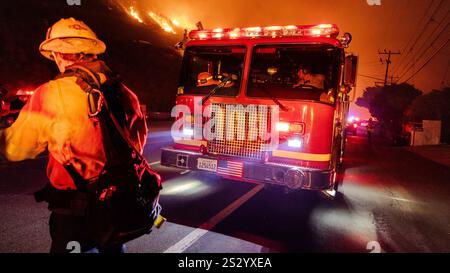 Malibu, California, Stati Uniti 7 gennaio 2025. Un Vigili del fuoco di LA County in un cappello da 89 è acceso rosso e giallo dalle luci dei veicoli di emergenza. Un incendio scoppiò il 7 gennaio 2025, come si vede dalla PCH (Pacific Coast Highway) nella ricca città di Pacific Palisades, ai margini di Malibu, CA, a causa di venti di Santa Ana insolitamente forti che superavano i 100 MPH (Credit Image: © Amy Katz/ZUMA Press Wire) SOLO PER L'USO EDITORIALE! Non per USO commerciale! Foto Stock