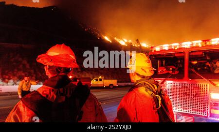 Malibu, California, Stati Uniti 7 gennaio 2025. Un Vigili del fuoco di LA County in un cappello da 89 è acceso rosso e giallo dalle luci dei veicoli di emergenza. Un incendio scoppiò il 7 gennaio 2025, come si vede dalla PCH (Pacific Coast Highway) nella ricca città di Pacific Palisades, ai margini di Malibu, CA, a causa di venti di Santa Ana insolitamente forti che superavano i 100 MPH (Credit Image: © Amy Katz/ZUMA Press Wire) SOLO PER L'USO EDITORIALE! Non per USO commerciale! Foto Stock