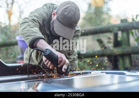 uomo con un dito ferito che usa una smerigliatrice elettrica Foto Stock