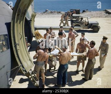 Un marine ferito evacuato su un Douglas Dakota DC-3. Il Dakota era un monoplano in metallo ad ala bassa con carrello di atterraggio convenzionale, alimentato da due motori radiali a pistoni, era veloce, con una buona autonomia, affidabile e in grado di operare da brevi piste. Durante la seconda guerra mondiale, furono costruite più di 10.000 versioni militari statunitensi del DC-3, con le forze armate di molti paesi che usavano il DC-3 e le sue varianti militari per il trasporto di truppe, merci e feriti. Foto Stock