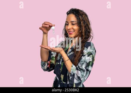 Estetista sorridente che versa olio essenziale a portata di mano per il trattamento della pelle, la bellezza e il concetto di salute Foto Stock