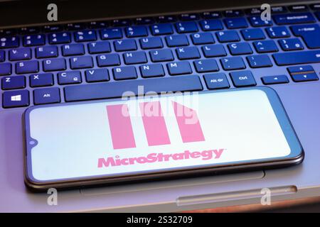 In questa immagine, il logo MicroStrategy Incorporated viene visualizzato sullo schermo di uno smartphone accanto alla tastiera di un notebook. Foto Stock