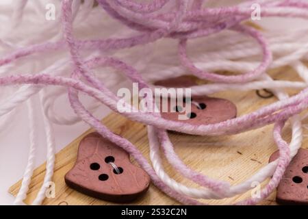 Bottoni di legno a cuore con filati viola e bianco da vicino. Foto di alta qualità Foto Stock