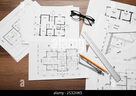 Diversi disegni architettonici, matita, righello, vetri e divisore su tavolo in legno, piatto Foto Stock