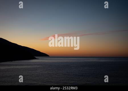 Immagina un tramonto mozzafiato che proietta colori vivaci su un tranquillo specchio d'acqua, con maestose montagne sullo sfondo. Santo Mo Foto Stock