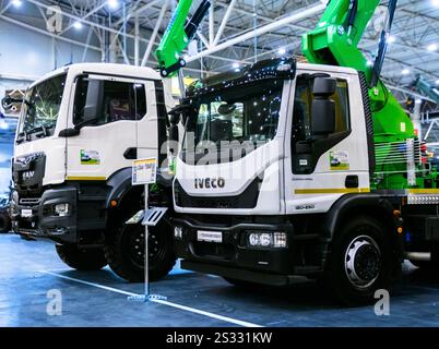 Kiev, Ucraina - 16 ottobre 2024: Due moderni camion commerciali IVECO sono parcheggiati in una sala coperta. Entrambi i carrelli sono bianchi e dotati di gru, per Foto Stock