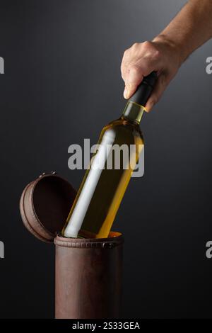 Il sommelier mette una bottiglia di vino bianco in una vecchia scatola di legno. Concetto di vino costoso. Copia spazio. Foto Stock