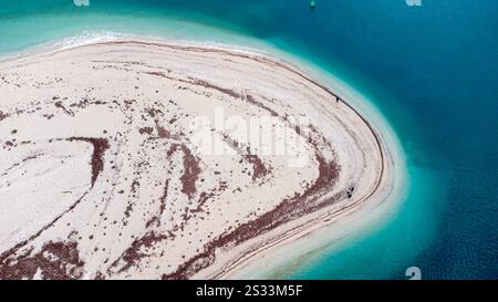 Questa immagine mostra una vista aerea mozzafiato di una piccola e affascinante isola situata nella vasta distesa dell'oceano, circondata da acque scintillanti Foto Stock