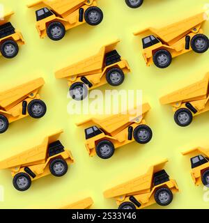 Molti piccoli giallo camion giocattolo su texture di sfondo di moda giallo pastello carta a colori nel concetto di minima. Foto Stock