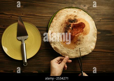Pizza Volcano tagliata a mano con forbici. Gorgonzola, pomodori ciliegini, verdure fresche e spezie. Foto Stock