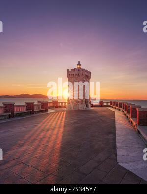 Vista al tramonto del faro di Piombino piazza Bovio e dell'Isola d'Elba sullo sfondo. Regione Toscana, Italia Foto Stock