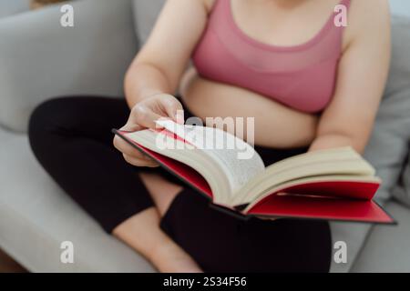 Donna in sovrappeso che legge un libro per perdere peso. Donna grassa preoccupata per la dieta del peso perdere stile di vita. Foto Stock