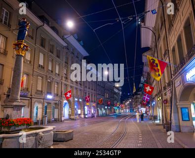 Bella strada della città Vecchia con il vecchio edificio e le bandiere a Dusk nella città di Berna, Canton Berna, Svizzera. Foto Stock