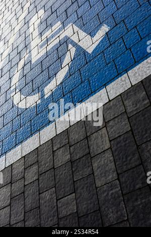 Contrassegno bianco e blu di un parcheggio per disabili in un parcheggio fatto di blocchi grigi. Disegno di una sedia a rotelle verniciata sulla superficie. Foto Stock