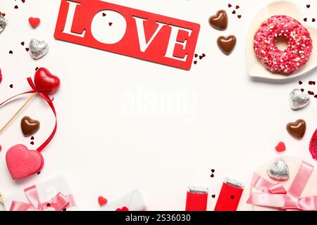 Cornice composta da diversi dolci gustosi, confezioni regalo e Love su sfondo bianco. Festa di San Valentino Foto Stock