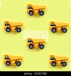 Molti piccoli giallo camion giocattolo su texture di sfondo di moda giallo pastello carta a colori nel concetto di minima. Foto Stock