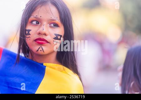 Giovane ragazza con la tradizionale vernice per il viso che celebra una festa nazionale avvolta da una bandiera colombiana Foto Stock