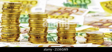 Pila di monete, curva discendente, foto simbolica per il calo dei tassi di interesse e dei costi Foto Stock