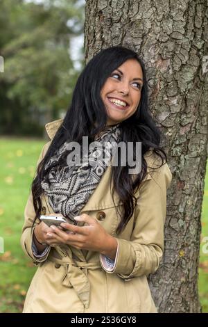 Una giovane donna scrive un messaggio di testo sul suo cellulare. Comunicazione con uno smartphone Austria Foto Stock