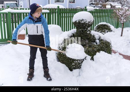 Un adolescente scaglia la nuova neve da un sentiero. Inizio dell'inverno in Austria Foto Stock