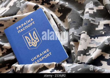 Passaporto straniero ucraino su tessuto con tessuto di camouflage pixed militare. Panno con motivo camo in pixel grigio, marrone e verde e Regno Unito Foto Stock