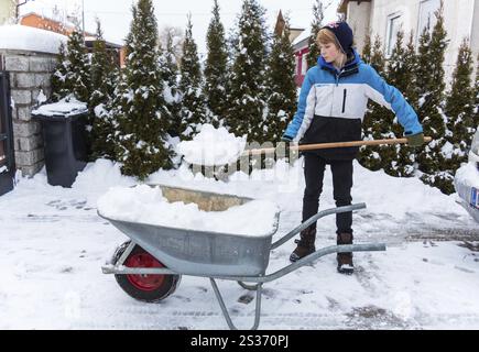 Un adolescente scaglia la nuova neve da un sentiero. Inizio dell'inverno in Austria Foto Stock