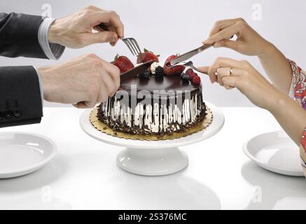 Due persone con coltelli e forchette pronto a mangiare tutta la torta al cioccolato a destra dal cavalletto. Foto Stock