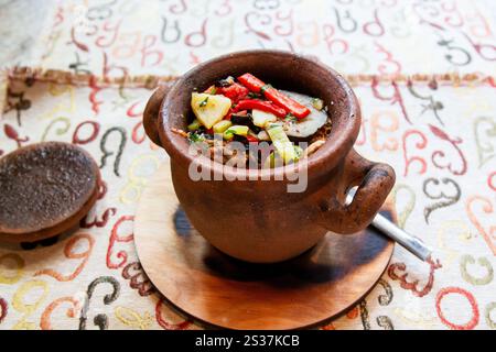 Viaggia verso la Georgia - porzione di Chanakhi (piatto tradizionale georgiano di stufato di agnello con pomodori, melanzane, patate, verdure e aglio) in pentola in loca Foto Stock