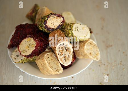 Molti panini di delizia turca con diversi sapori e ripieni in piatto bianco sul tavolo. Tagli di dolci Turk Lokumu. Molti panini di delizia turca Foto Stock