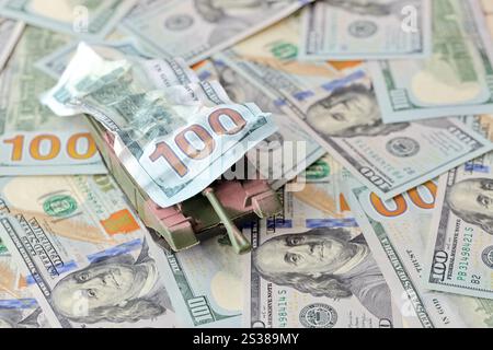 Carro armato su banconote da cento dollari schiacciate. Contesto del finanziamento di guerra e del prezzo di supporto militare per gli Stati Uniti d'America. Serbatoio su deformato Foto Stock