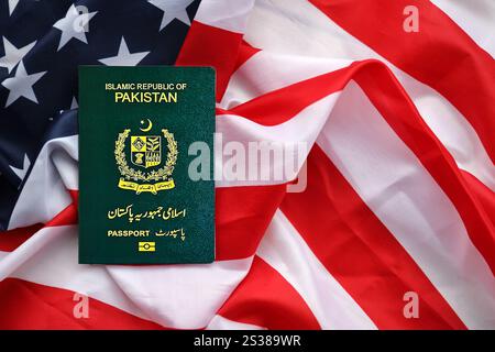 Passaporto verde della Repubblica Islamica del Pakistan sullo sfondo della bandiera nazionale degli Stati Uniti da vicino. Concetto di turismo e diplomazia Foto Stock