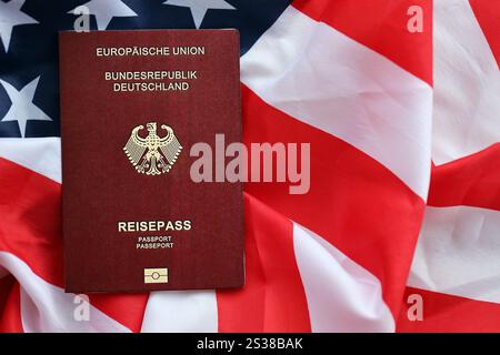 Passaporto tedesco rosso dell'Unione europea sullo sfondo della bandiera nazionale degli Stati Uniti da vicino. Concetto di turismo e diplomazia. Passaporto tedesco rosso di Foto Stock