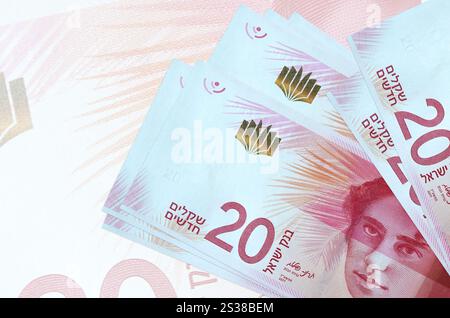 20 nuove banconote israeliane giacciono in pila sullo sfondo di una grande banconota semi-trasparente. Presentazione astratta della moneta nazionale. Affari Foto Stock