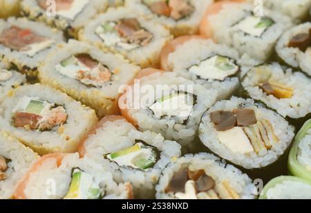 Primo piano di molti panini di sushi con ripieni diversi giacciono su una superficie di legno. Macro shot di cucina giapponese classica cucinata con uno spazio copia. Foto Stock